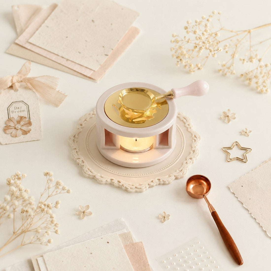 Wax sealing setup with a brass wax seal spoon, melting wax, handmade paper, dried flowers, and decorative stationery.
