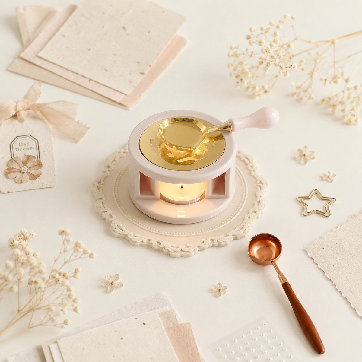 Wax sealing setup with a brass wax seal spoon, melting wax, handmade paper, dried flowers, and decorative stationery.