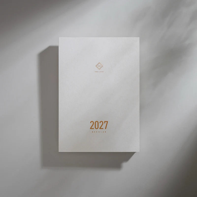 2027 Regular Planner A5 by Take a Note — near-white cover with gold-foil lettering and geometric logo, for journaling & planning