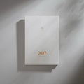 2027 Regular Planner A5 by Take a Note — near-white cover with gold-foil lettering and geometric logo, for journaling & planning