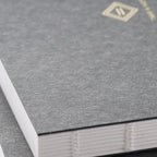 Close-up of a textured gray book with a gold emblem on a matching gray background