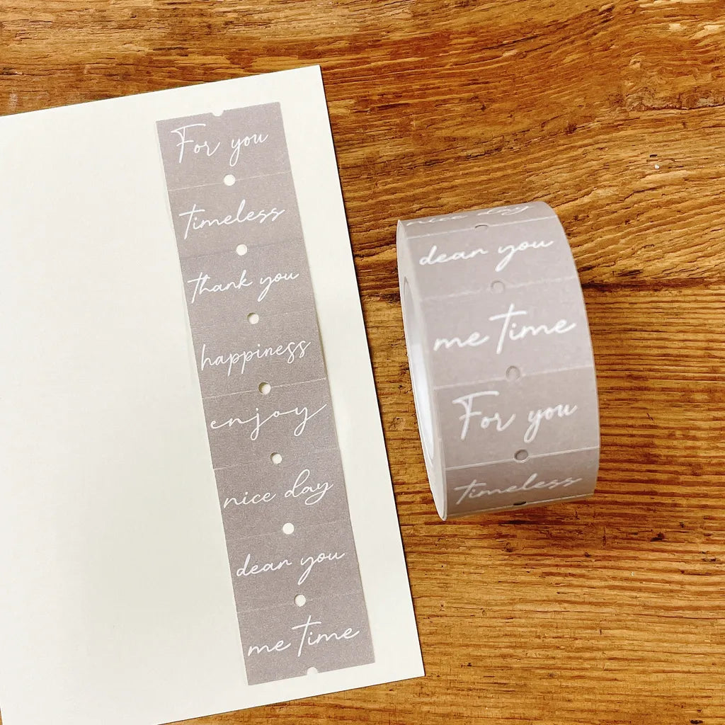Roll of Heart Words Label Sticker Tape with printed heartfelt phrases on a wooden surface