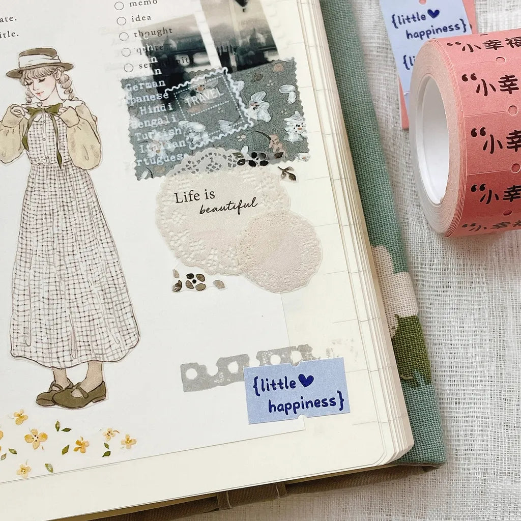 Open notebook decorated with Little Happiness Label Sticker Tape and washi on a textured surface
