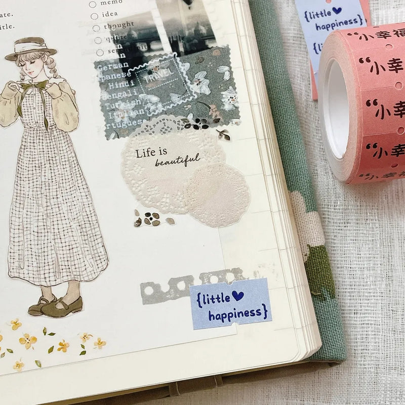 Open notebook decorated with Little Happiness Label Sticker Tape and washi on a textured surface