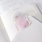 Red Ribbon Journaling Clip by Dodolulu — pink figure-shaped acrylic clip on an open notebook, for journaling