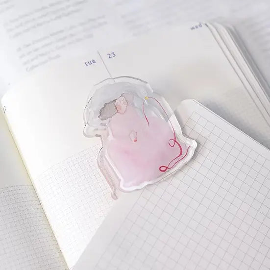 Red Ribbon Journaling Clip by Dodolulu — pink figure-shaped acrylic clip on an open notebook, for journaling