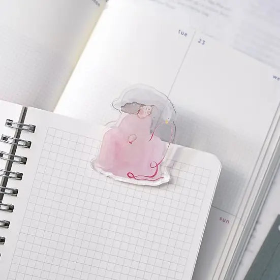 Red Ribbon Journaling Clip by Dodolulu — translucent pink figure acrylic clip on a grid notebook, for journaling