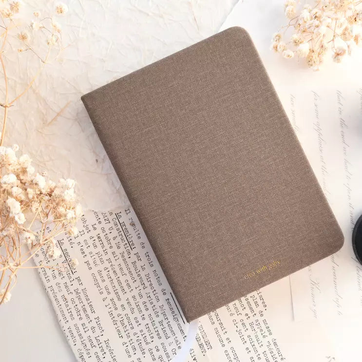 A6 Blank Notebook in brown with gold text styled with dried flowers on a white surface