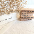 Stack of wooden blocks with 'a hug in a mug' text on a soft surface with dried flowers.