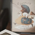 Book cover with a cartoon character holding an umbrella and a suitcase, titled 'A Journey without Magic'.