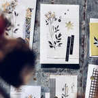 Collection of cards with floral designs and text on a textured surface