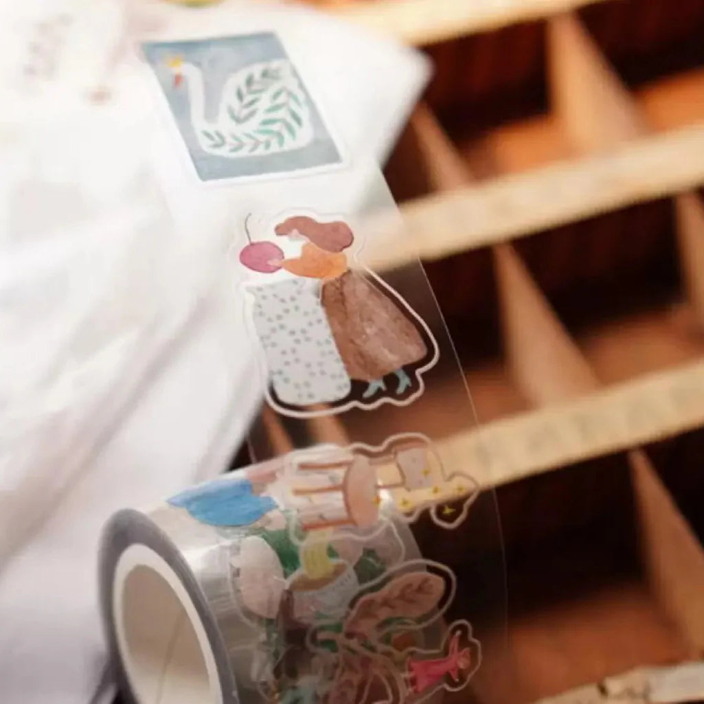 Roll of A Lovely Day PET Tape with playful cartoon characters styled on a wooden shelf, close-up