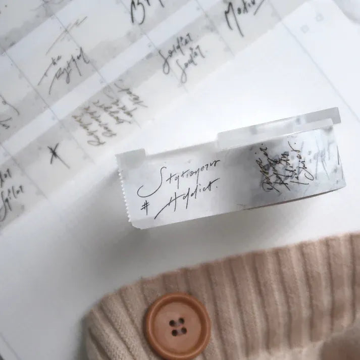 Close-up of an Addict Washi Tape strip with button and text detail on a textured craft surface
