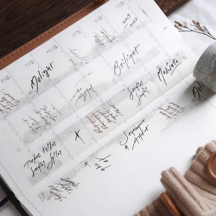 Roll of Addict Washi Tape made from recycled newspaper with script text on a warm wooden surface