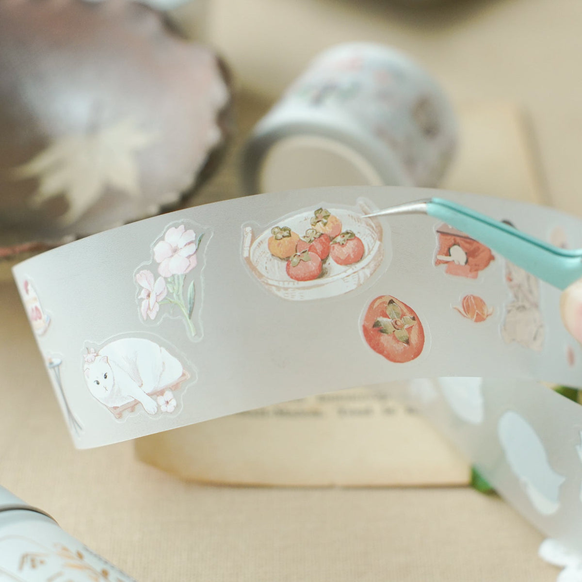 Hand holding a strip of Aki No Heya PET Tape with animal and fruit designs, detail view