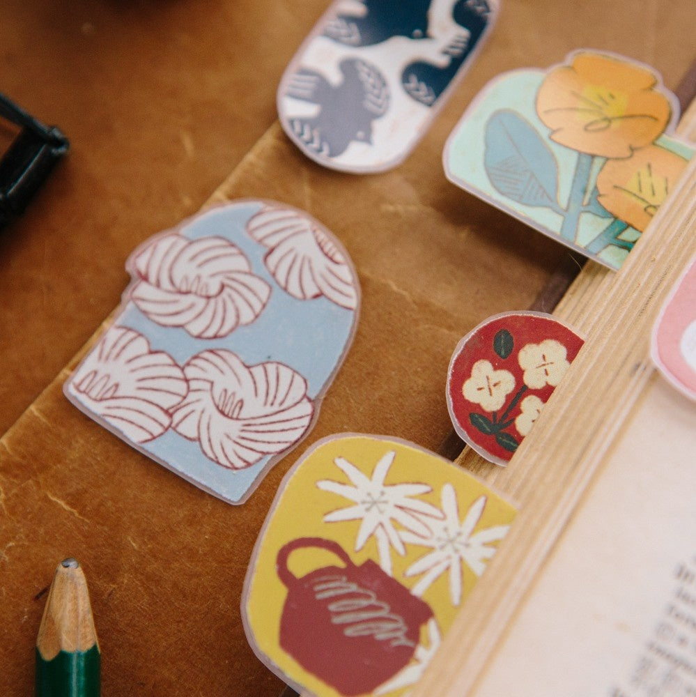 Decorative stickers with floral and teapot designs on a wooden surface.