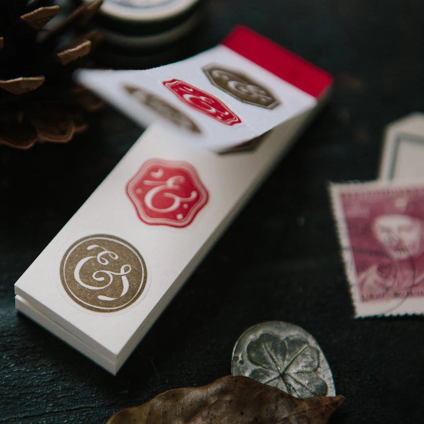 Close-up of the Ampersand Letterpress Memo Pad deck with coins and leaves on a dark surface