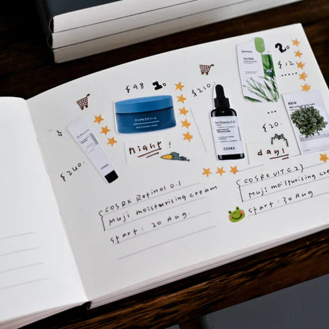 Anytime Anywhere Journal open to a lifestyle spread with cosmetic products and handwritten notes on a wooden table