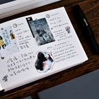 Journal with stickers and handwritten notes on a wooden surface