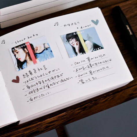 Anytime Anywhere Journal open to a memory-keeping spread with pasted photos and captions on a wooden desk