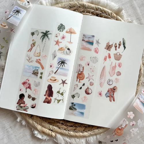 Open book with beach-themed stickers on a woven surface