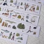 Illustrated paper strips with people and nature scenes on a textured surface