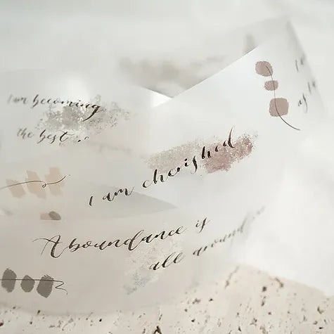 Textured paper with Attic Calligraphy PET Tape motivational phrases and floral designs on a light backdrop