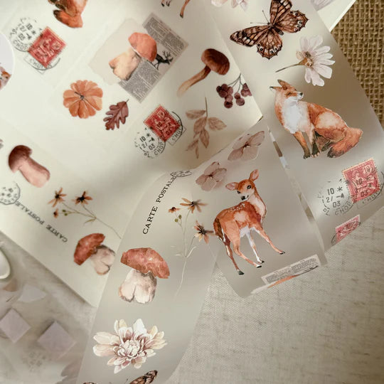 Collection of Autumnal PET Tape woodland animal and plant designs arranged on a textured surface, top view