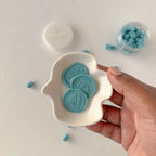 Hand holding a white dish with blue decorative elements on a light background