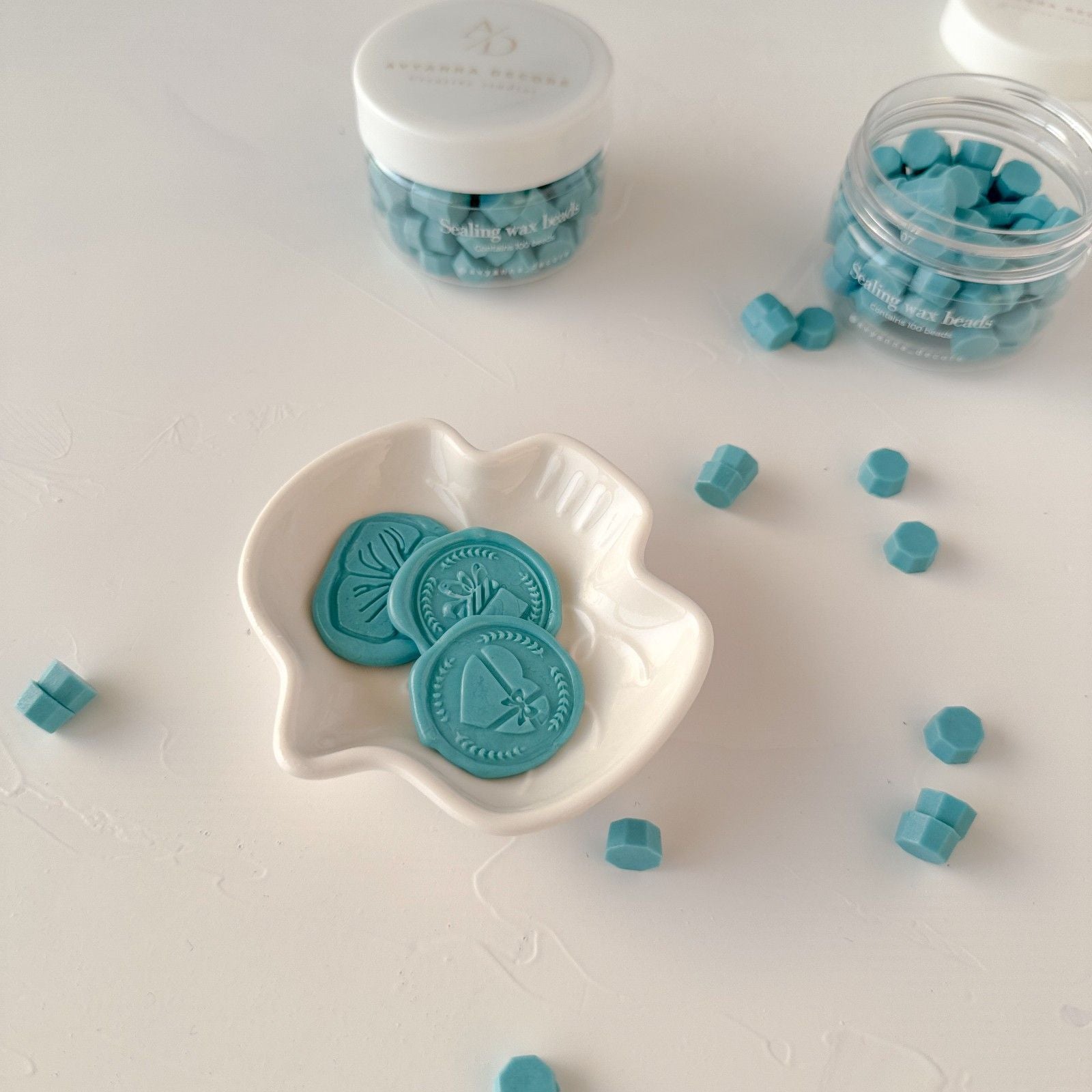 Teal candy pieces in a white dish and jars on a light background
