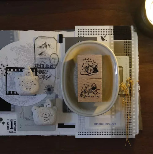 Wooden stamp with cartoon design on a white dish, surrounded by stationery items on a wooden surface.