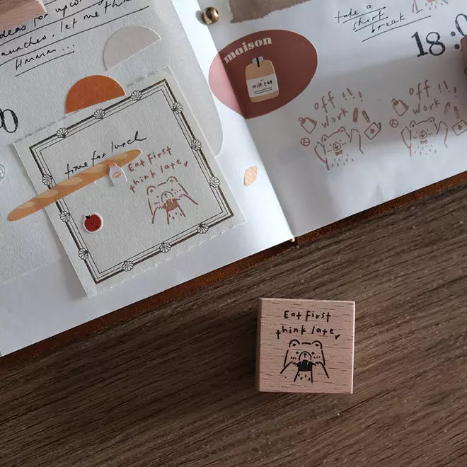 Beary Ordinary Days 02 Eat First stamp on a wooden surface with a book in the background