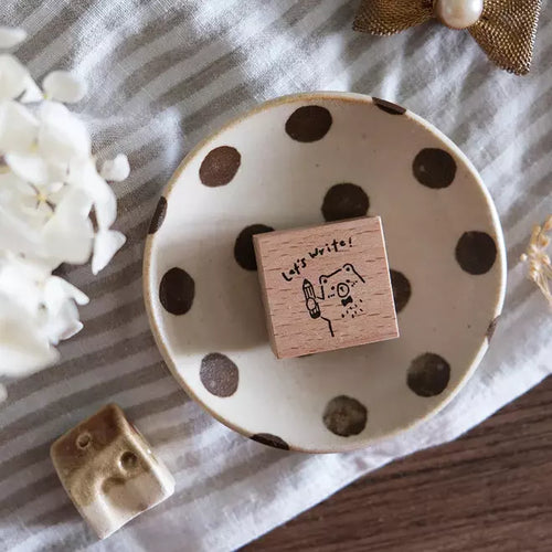 Polka dot ceramic dish with a wooden block and decorative elements on a striped fabric background