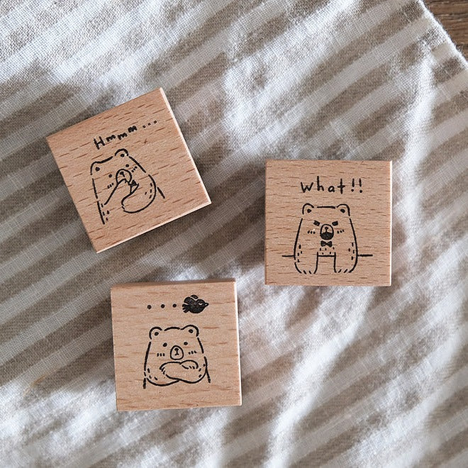 Three wooden stamps with bear illustrations on a striped fabric background