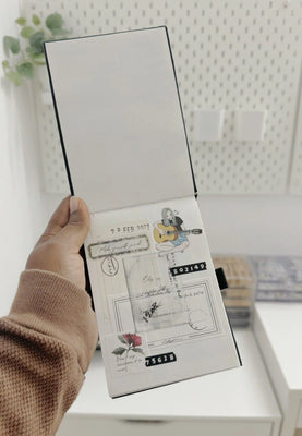 Hand holding a product packaging with design elements on a white surface.