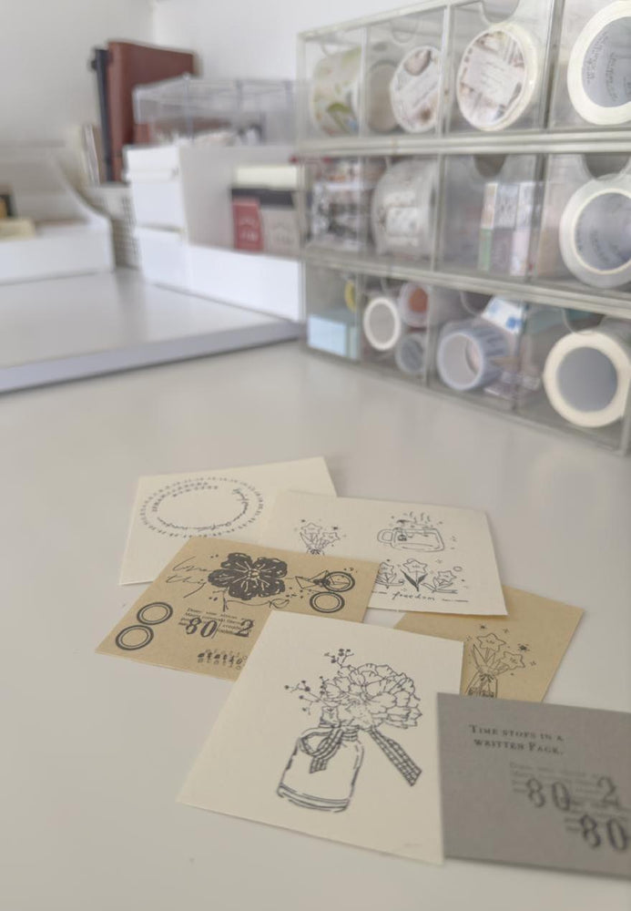 Collection of greeting cards with printed designs on a table, with stamping supplies in the background.