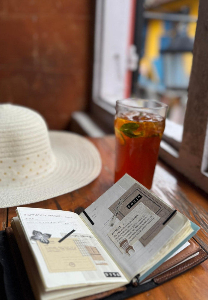 Open book with tea and a hat on a wooden table
