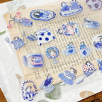 Blue and white vintage-style PET tape stickers with hand-drawn girls and ceramic-themed illustrations arranged on book page