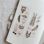 Sheet of decorative stickers with fashion and nature-themed designs on a textured surface.
