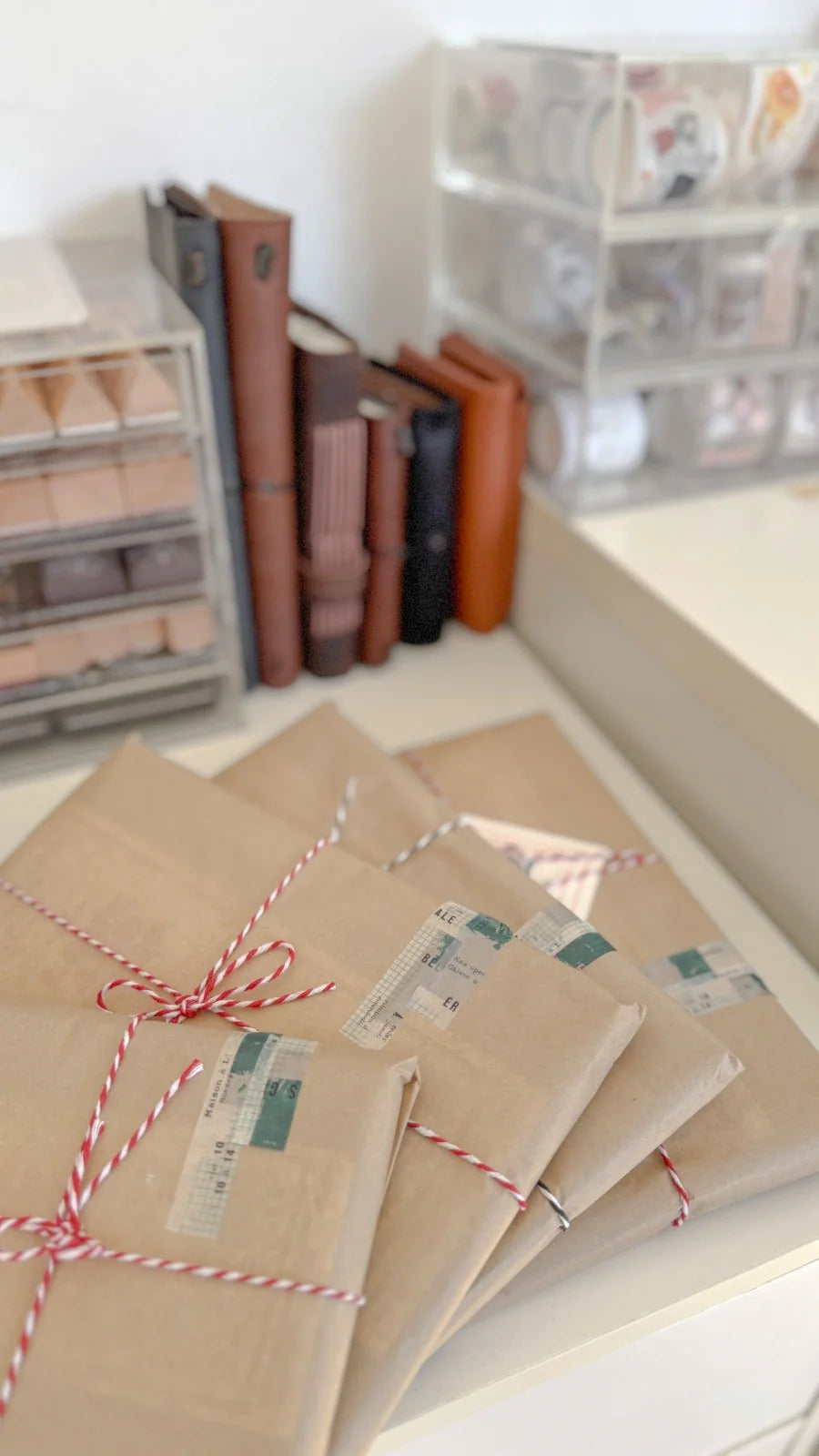 Kraft paper envelopes tied with string on a desk with books in the background