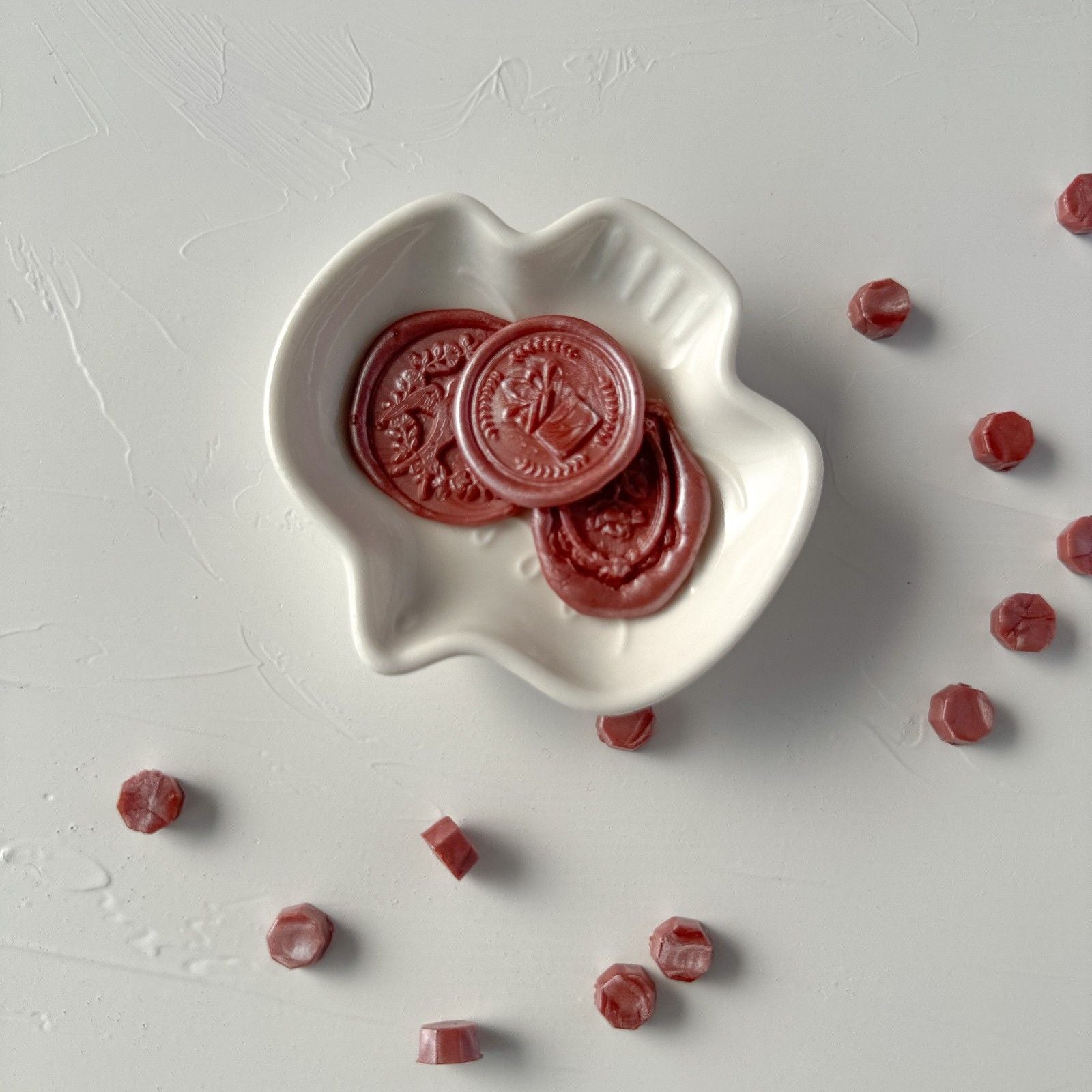 Red jelly candies in a white heart-shaped bowl on a light gray surface