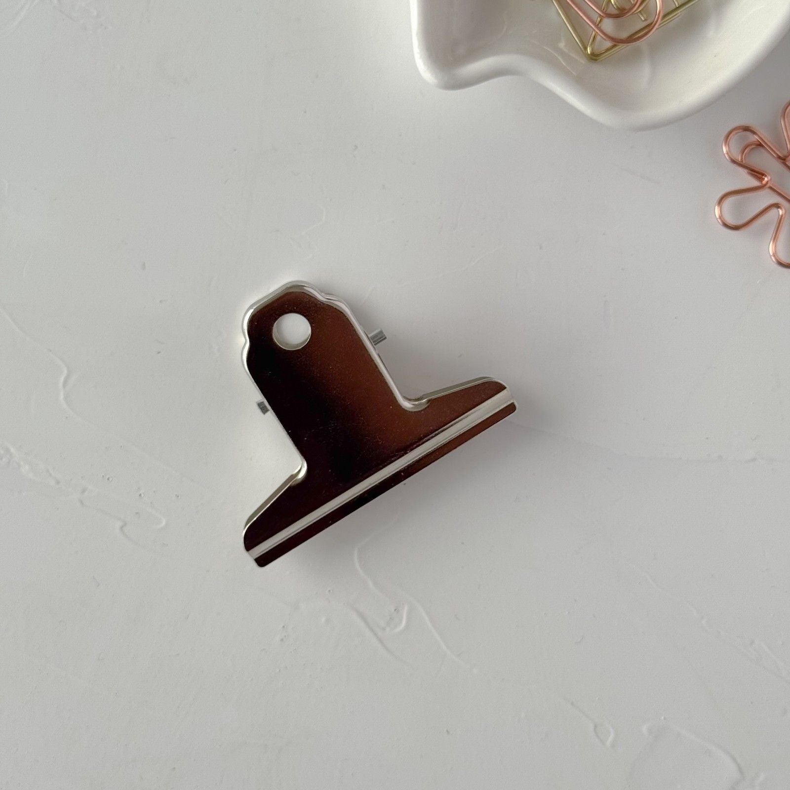 Metallic paper clip on a light gray surface
