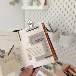 Medium 1.5 inch Bulldog Clip holding an open illustrated book, shown against a soft backdrop