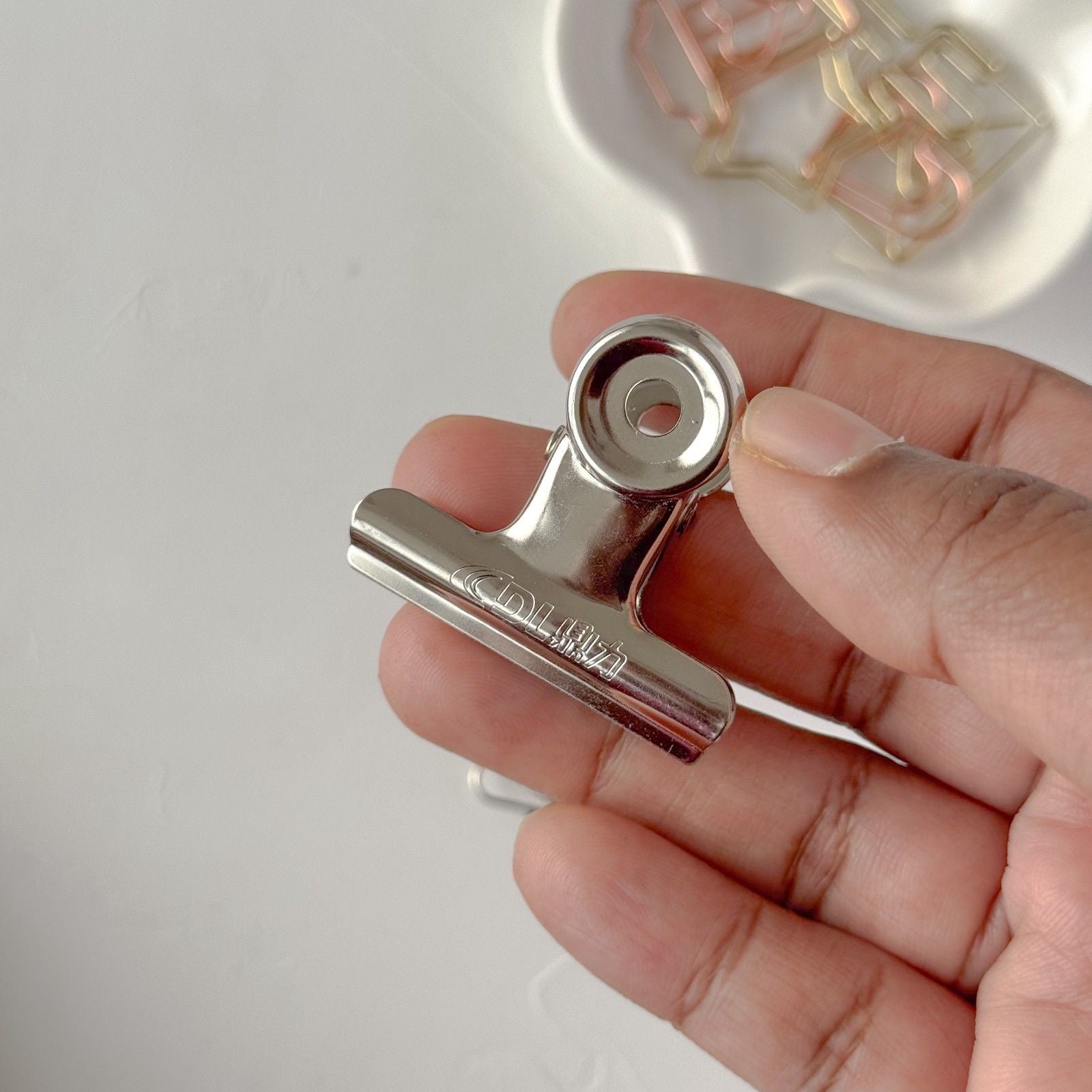Hand holding a metal clip against a light background