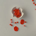 Red wax seals and a white dish on a light gray background