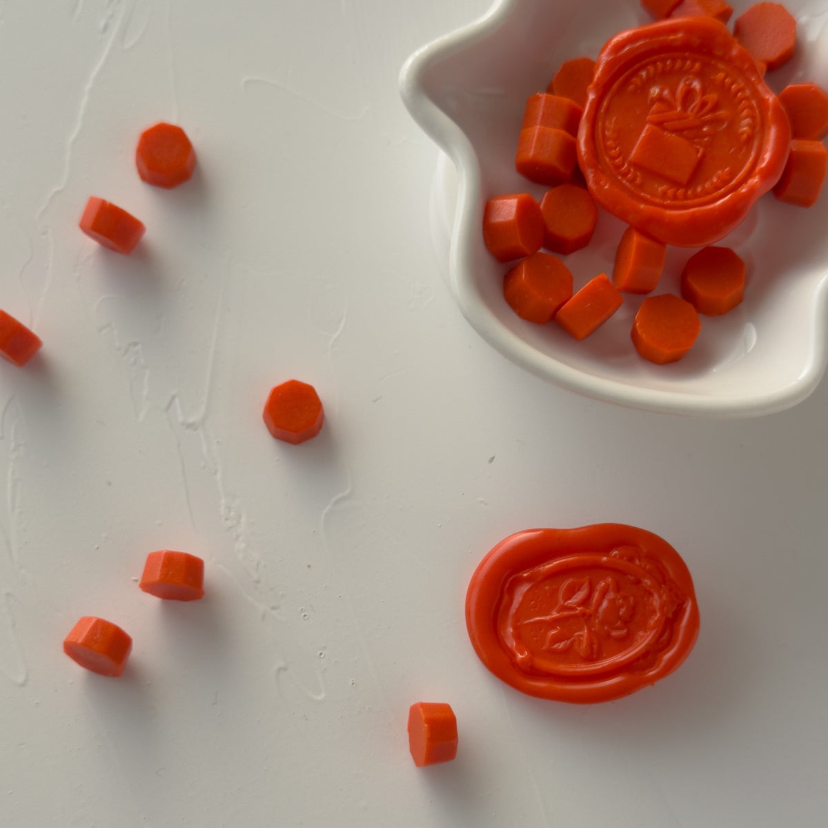 Stamped Burnt Orange sealing wax seals showing crisp engraved detail, close-up view on a white surface
