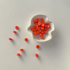 White leaf-shaped dish filled with red circular objects on a light gray background