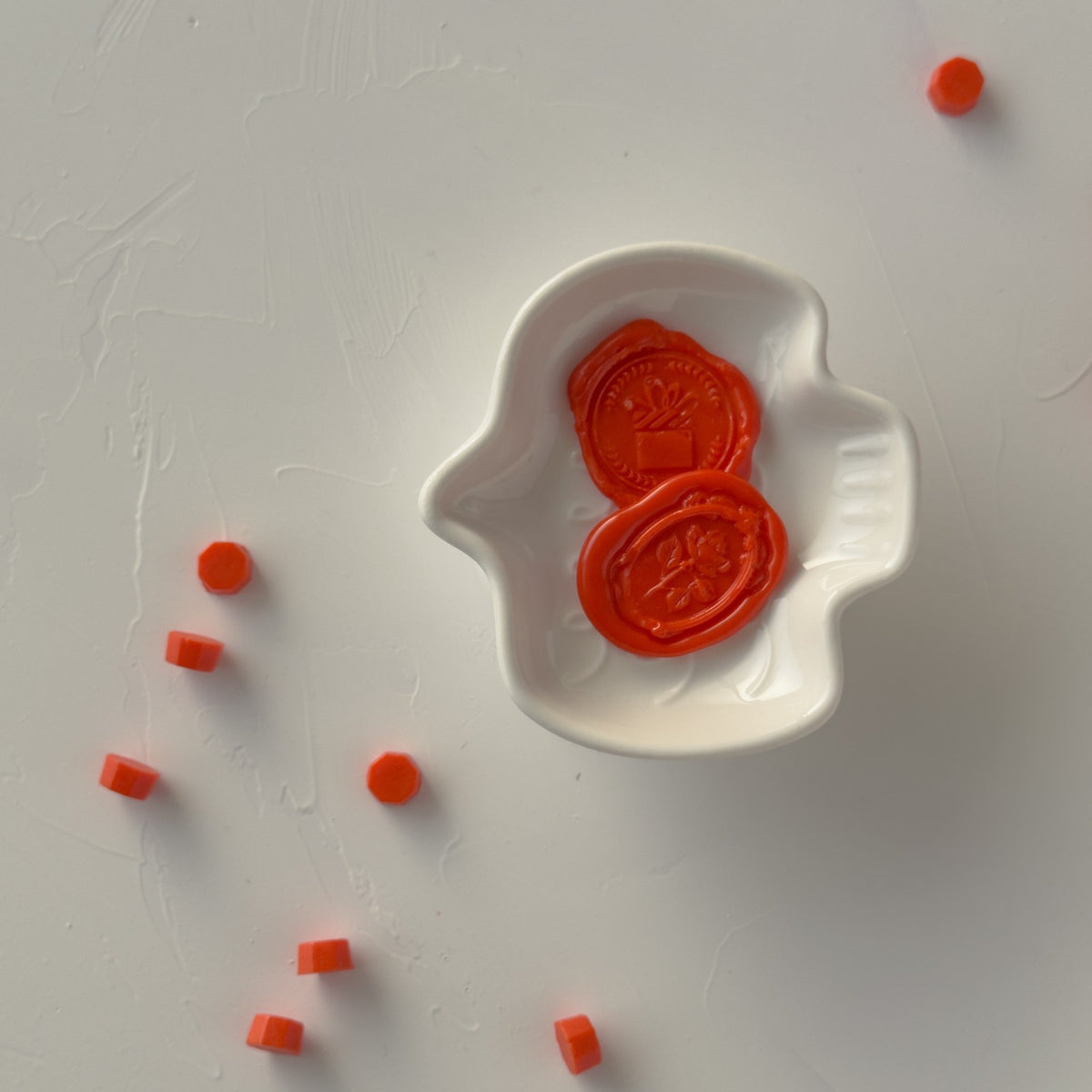 Burnt Orange wax seals resting on a white mold with loose beads scattered around, overhead flat lay