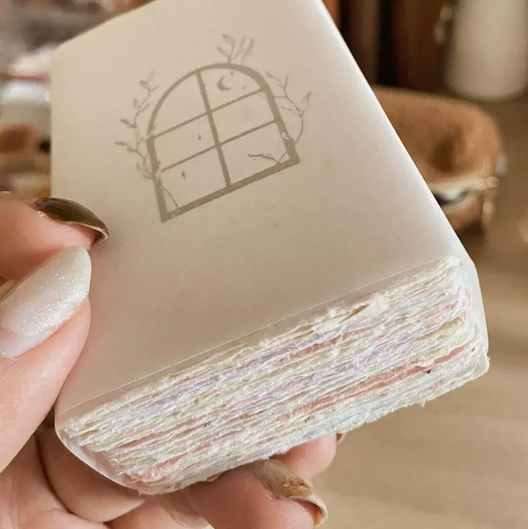 Hand holding a stack of Handmade Paper Business Cards with a decorative logo card on top