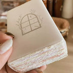Hand holding a layered cake with a decorative window design on top